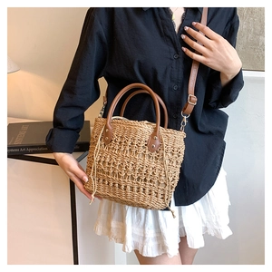 Detail of hand-woven straw bucket bag with brown leather straps and drawstring closure