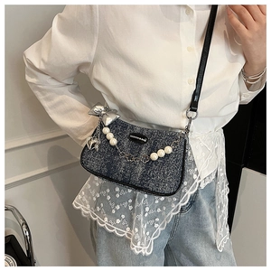 Détail du sac sous l'aisselle en denim avec perles et nœud argenté sur mannequin