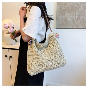 Detail of hollow floral weave on straw tote with colorful ethnic pattern strap