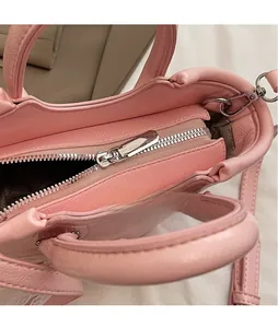 Close-up of smooth silver metal zipper and leather texture on a pink crossbody bag