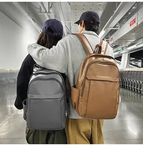 Detail view of large capacity waterproof PU leather backpacks worn by models in grey and brown