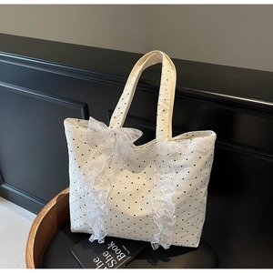 Gros plan sur un cabas en toile à pois blancs avec bordure en dentelle et grand nœud