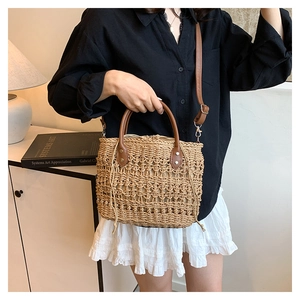 Close-up of woven straw bucket bag featuring leather straps and drawstring closure detail