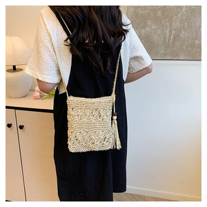 Detailed close-up of beige woven bucket bag with tassels on a female model