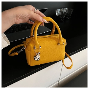 Détail du sac Boston en cuir jaune vif avec pendentif sifflet argenté et bandoulière