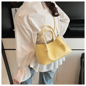 Détail du sac à bandoulière tressé jaune clair montrant la texture en similicuir et la sangle