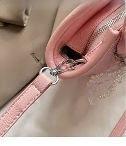 Close-up of pink lychee leather bag with silver hardware, lace edge and pearl chain