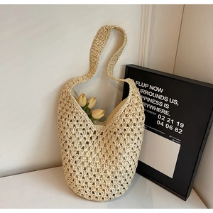 Detail view of woven straw shoulder bag featuring a large mesh pattern and tulip accents