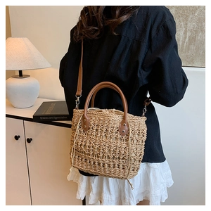 Detail of hand-woven straw bucket bag with brown leather handle and drawstring closure