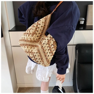 Detail view of hand-woven straw tote bag with geometric pattern and slim leather straps