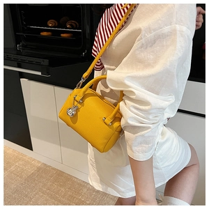 Détail d'un sac Boston jaune en cuir grainé avec pendentif argenté en décor cuisine
