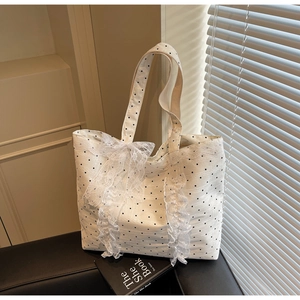 Détail d'un cabas en toile à pois blancs orné d'un grand nœud en dentelle et de volants doux