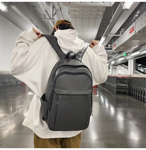 Rear view of a modern minimalist dark grey faux leather backpack on a model's back