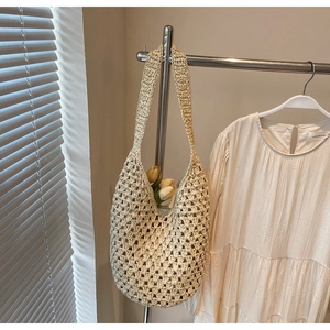 Detailed mesh texture of an ivory woven hollow shoulder bag in a sunlit aesthetic setting
