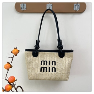 Close-up of woven straw bag detail featuring min min embroidery and black leather straps