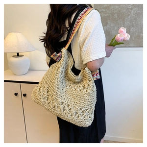 Detail of hollow floral woven pattern on beige straw tote bag with colorful strap