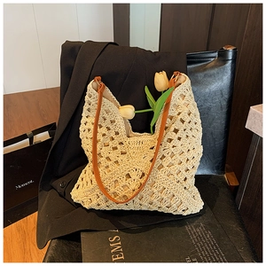Detailed close-up of woven straw tote bag with brown PU straps and hollow knit texture