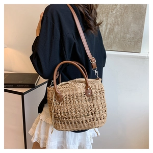 Detail view of straw woven bag featuring leather handles and beige drawstring inner pouch
