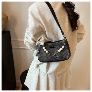 Détail du sac sous le bras en tweed avec nœud argenté et perles porté par le mannequin