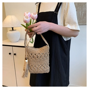 Detail of woven straw bucket bag featuring floral patterns and tassel bead accents