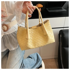 Détail du sac cabas tissé jaune clair avec tissage diagonal et doubles poignées rondes
