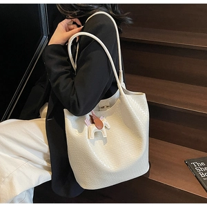 White large tote bag with crocodile texture and Pegasus charm shown on a shoulder