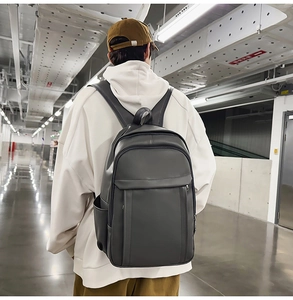 Minimalist large-capacity dark grey leather backpack shown on back in industrial setting