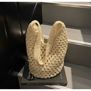 Detail of hollow woven shoulder bag showing beige raffia texture and fabric lining