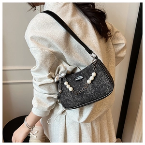 Détail d'un sac porté épaule noir pailleté avec chaîne de perles et pendentif nœud argenté