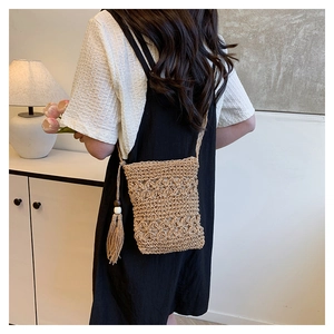 Detail of hand-woven straw bucket bag with floral cutouts and long tassels