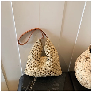 Detail of hollow-out weave pattern on beige straw tote bag with brown leather strap