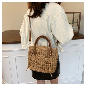 Detail view of woven straw bucket bag with brown PU leather handle and drawstring closure