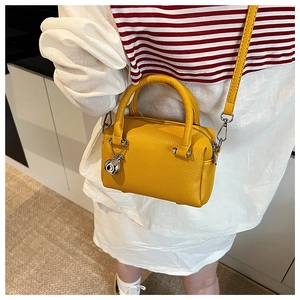 Sac Boston jaune moutarde en cuir litchi porté en bandoulière avec breloque cochon