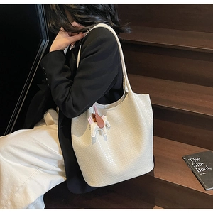 Detail of white woven textured tote bag with a colorful leather horse charm accessory