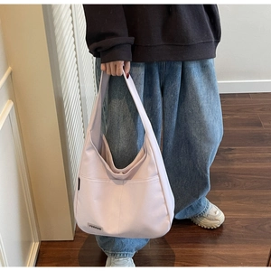 Detail of light pink canvas hobo bag with front pocket and woven label for women