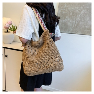 Detailed close-up of straw woven tote bag with hollow floral pattern and colorful strap