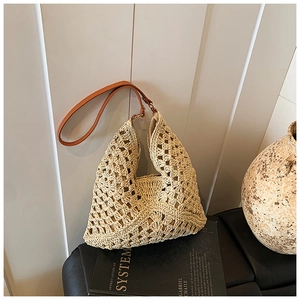 Close-up of beige crochet tote bag with hollow floral pattern and brown leather strap