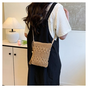 Detail of hand-woven hollow flower pattern on straw bucket bag with wooden bead tassels