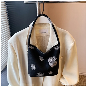 Detailed close-up of a black canvas bucket bag with white floral patterns on a blazer