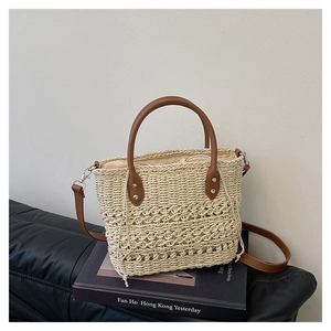 Detail of woven straw bucket bag with brown leather handles and drawstring closure