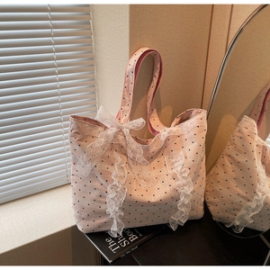 Détail du sac cabas rose à pois avec bords en dentelle blanche et un nœud décoratif