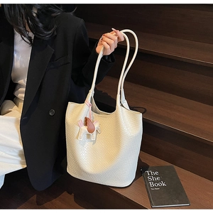 Detailed woven texture of white bucket tote bag featuring a pink Pegasus charm on stairs