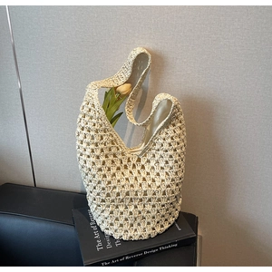 Detail of hollow woven straw shoulder bag in cream white with decorative tulip flower