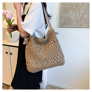 Detail of hand-woven straw tote bag featuring colorful braided straps and floral texture