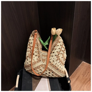 Detail of hollow crochet straw tote bag with brown leather strap and floral pattern