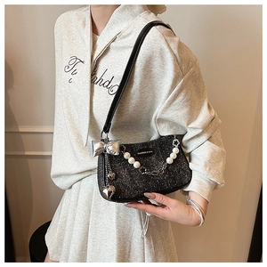 Detail of black sequined handbag with silver bow, heart charms and pearl chain