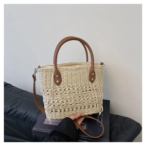 Detail of hand-woven straw bucket bag with brown leather handles and drawstring lining