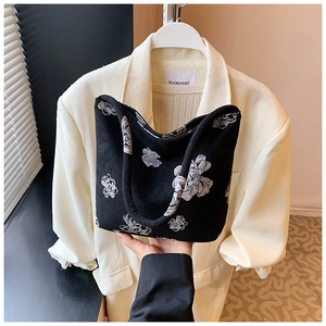 Close-up of black canvas bucket bag with white floral patterns and texture details