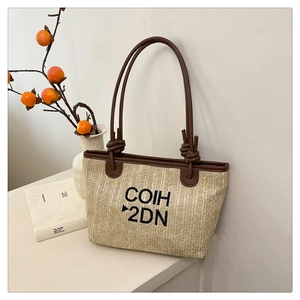 Detailed view of woven tote bag with COIH 2DN embroidery and brown leather strap knots