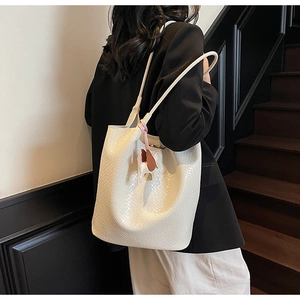 Detailed woven texture of off-white bucket bag with a leather pony charm on the side